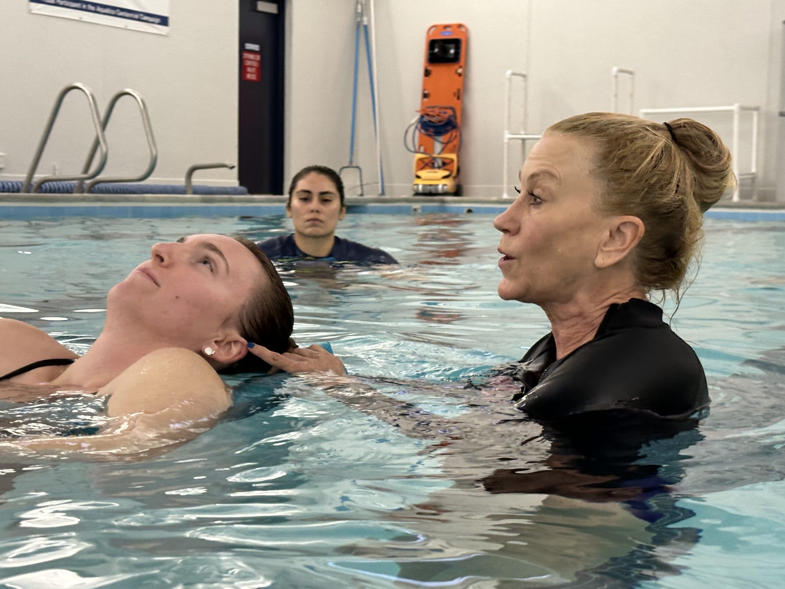 Cindy Freedman is demonstrating an adaptive swi coaching technique on participant in an in-water training session